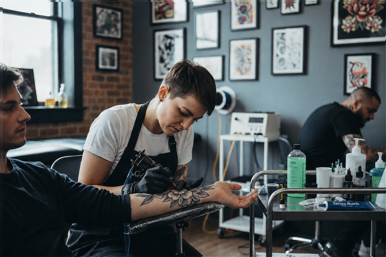 Tattoo artist working in a professional studio with Perfso tattoo numbing cream and care cream placed on the work table